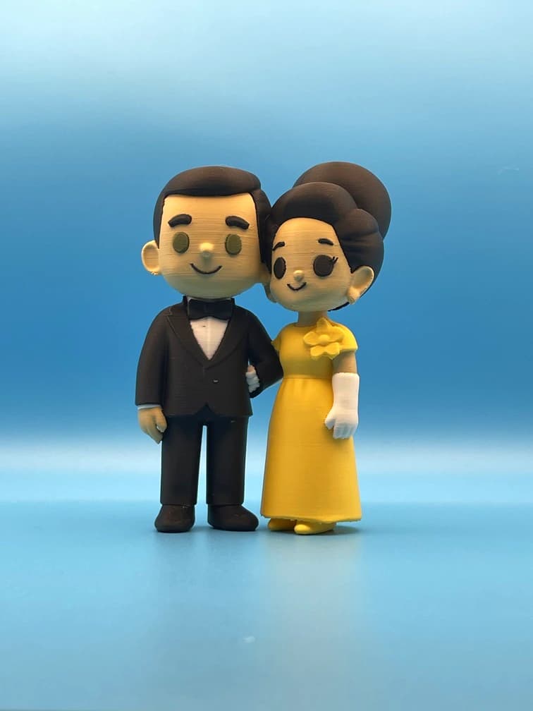 Custom couple figurines in a dark suit and yellow dress, with visible printed texture